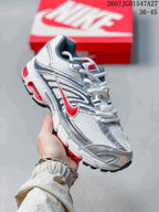 Angled side view of a Nike Air Max Moto 2K sneaker showing the white and silver construction, red branding accent, and textured sole.