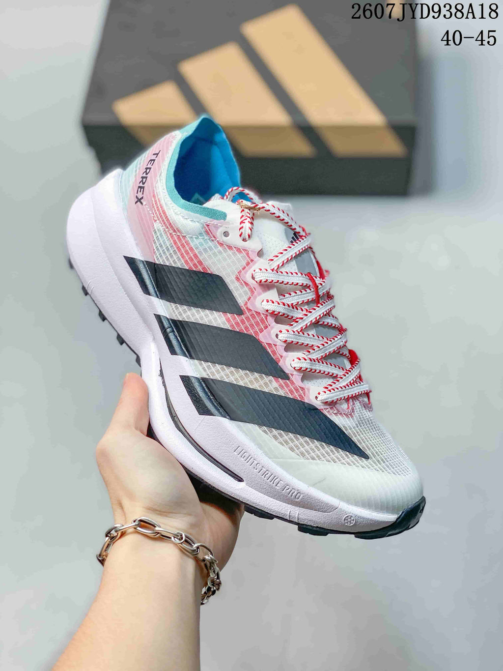 Angled side view of the white running shoe with pink and blue upper accents, black side details, white midsole, and textured outsole; size range text 40–45 is visible.