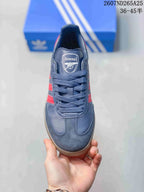 Top view showing the rounded toe, navy laces, tongue label, red side stripes, and Arsenal crest.
