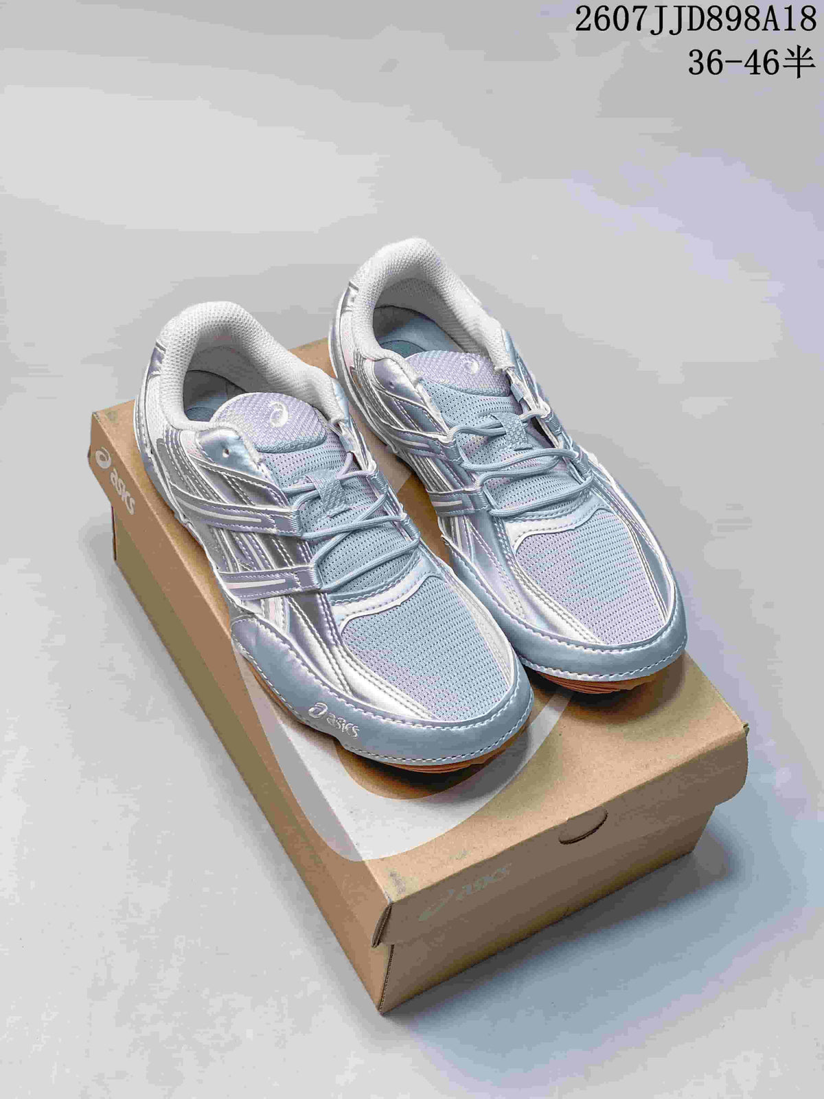 Pair of silver and gray ASICS Hypersync sneakers displayed on a shoebox; style code 2607JJD898A18 and size range 36–46 are visible.
