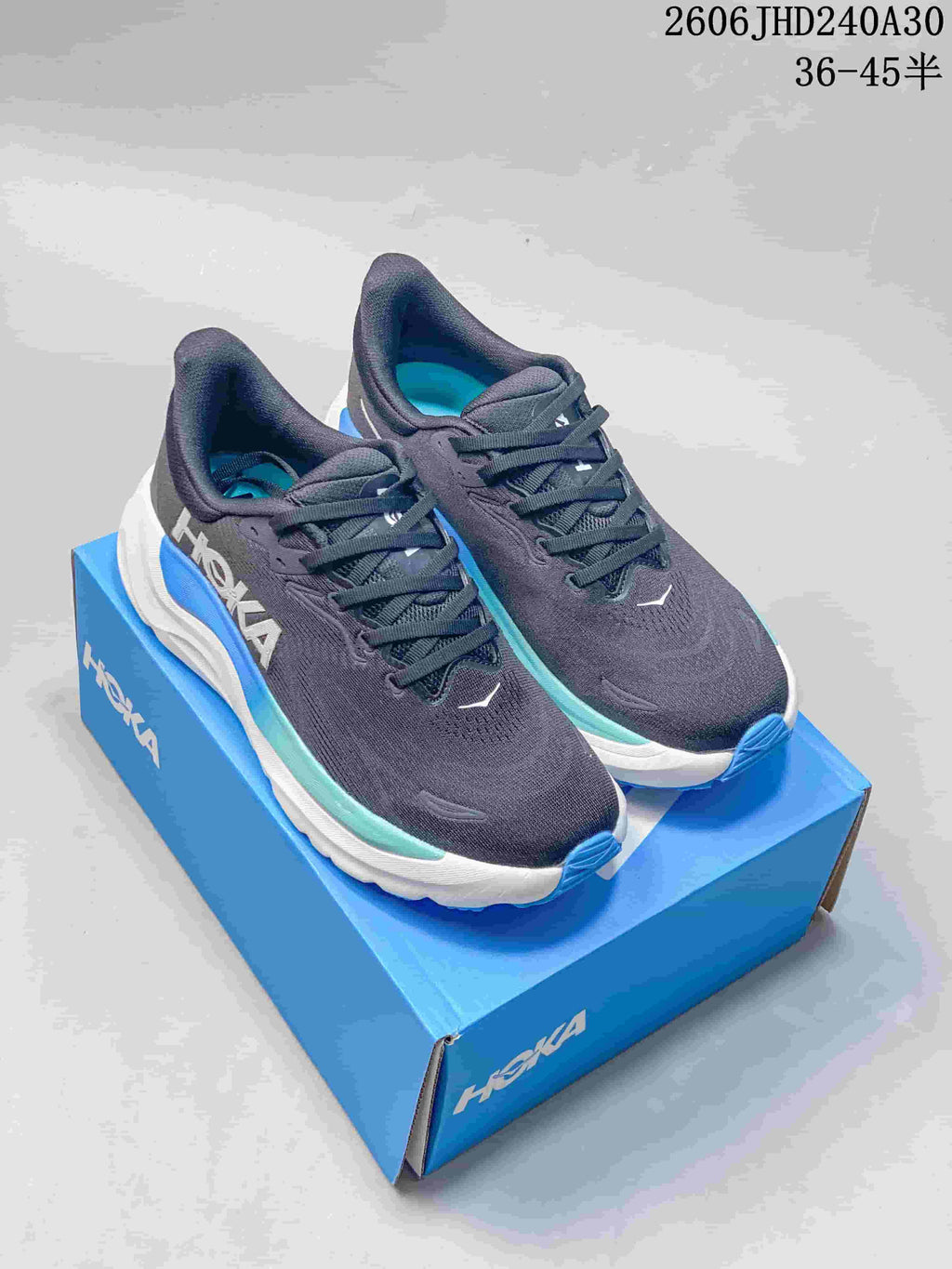 Pair of charcoal HOKA Arahi 8 running shoes with blue and aqua accents on a blue shoe box.
