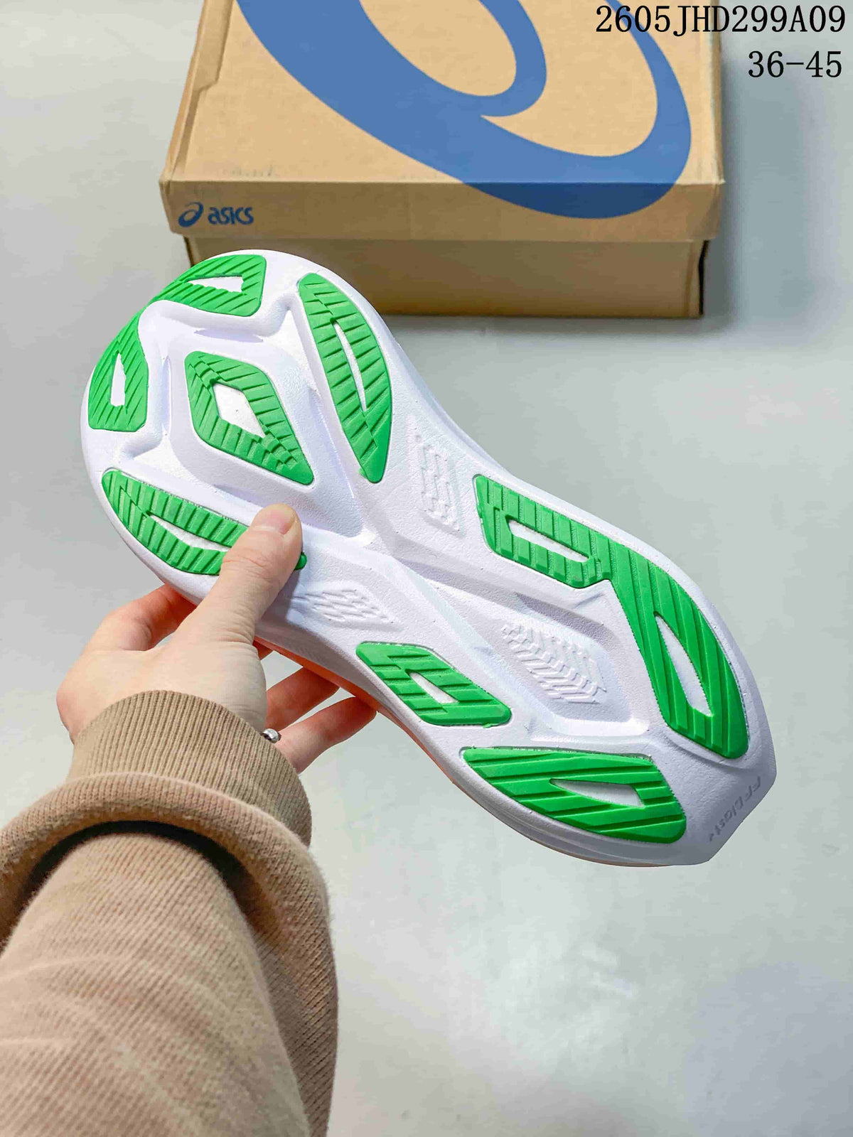 Underside of the running shoe showing a white outsole with green tread sections