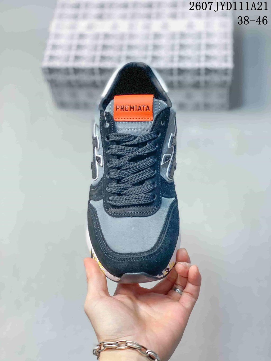 Top-down view of the sneaker showing dark laces, grey upper panels and an orange Premiata tongue label.