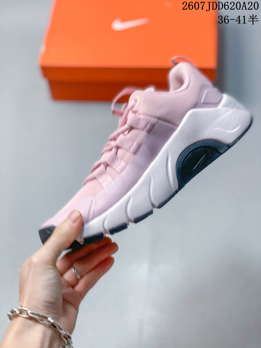 Side profile of the pink and white training shoe showing the layered upper, lace supports, sculpted midsole, and dark outsole sections.