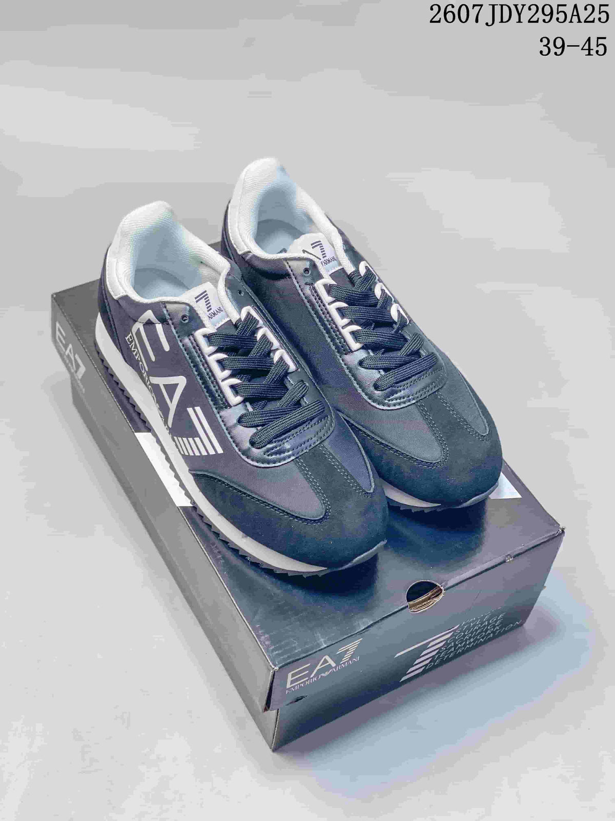 Pair of navy and white Emporio Armani EA7 lace-up sneakers displayed on the branded shoebox; image text shows style code 2607JDY295A25 and size range 39-45.