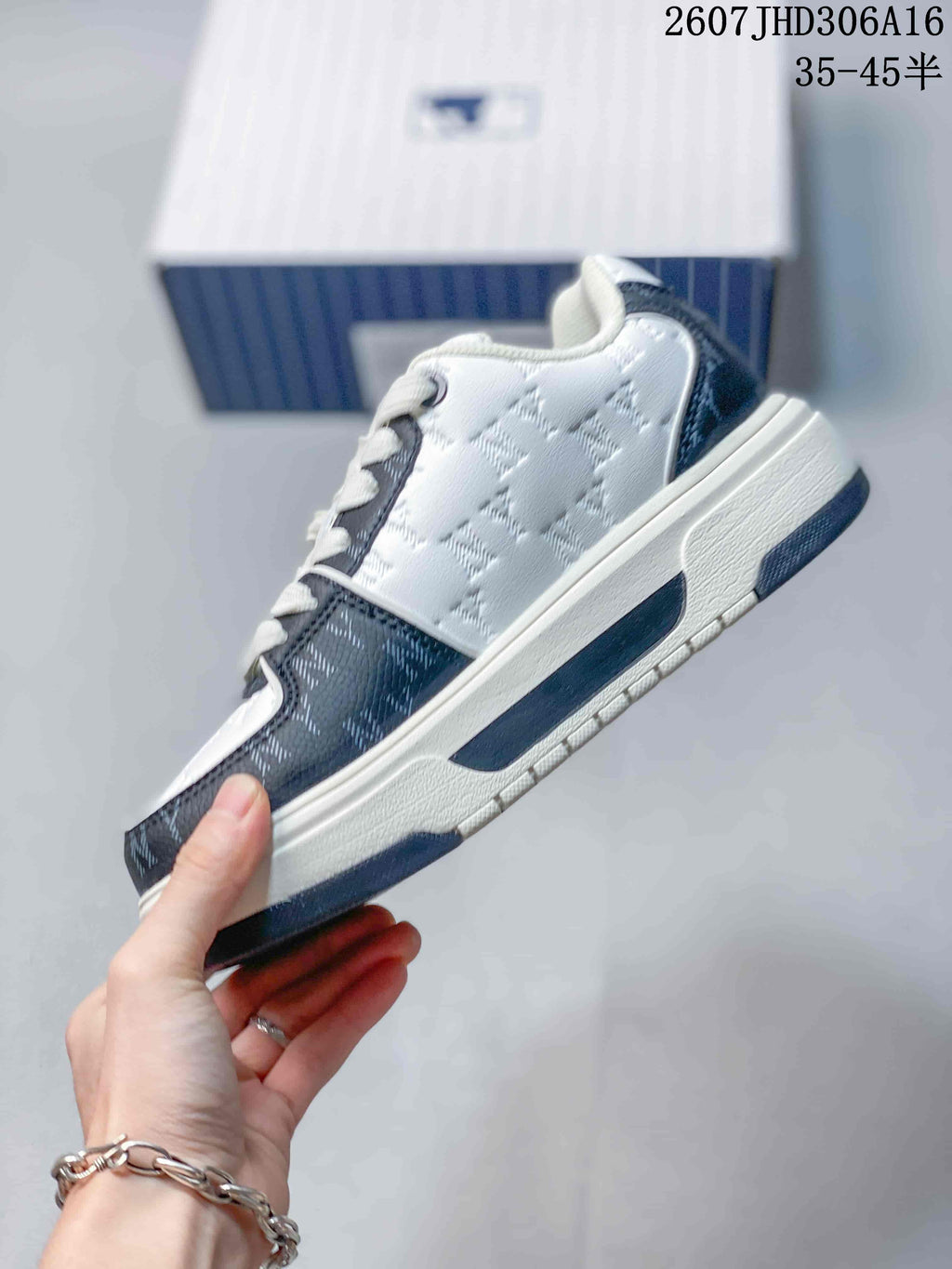 Side view of the white and navy low-top sneaker showing its layered sole, patterned upper, and side branding.
