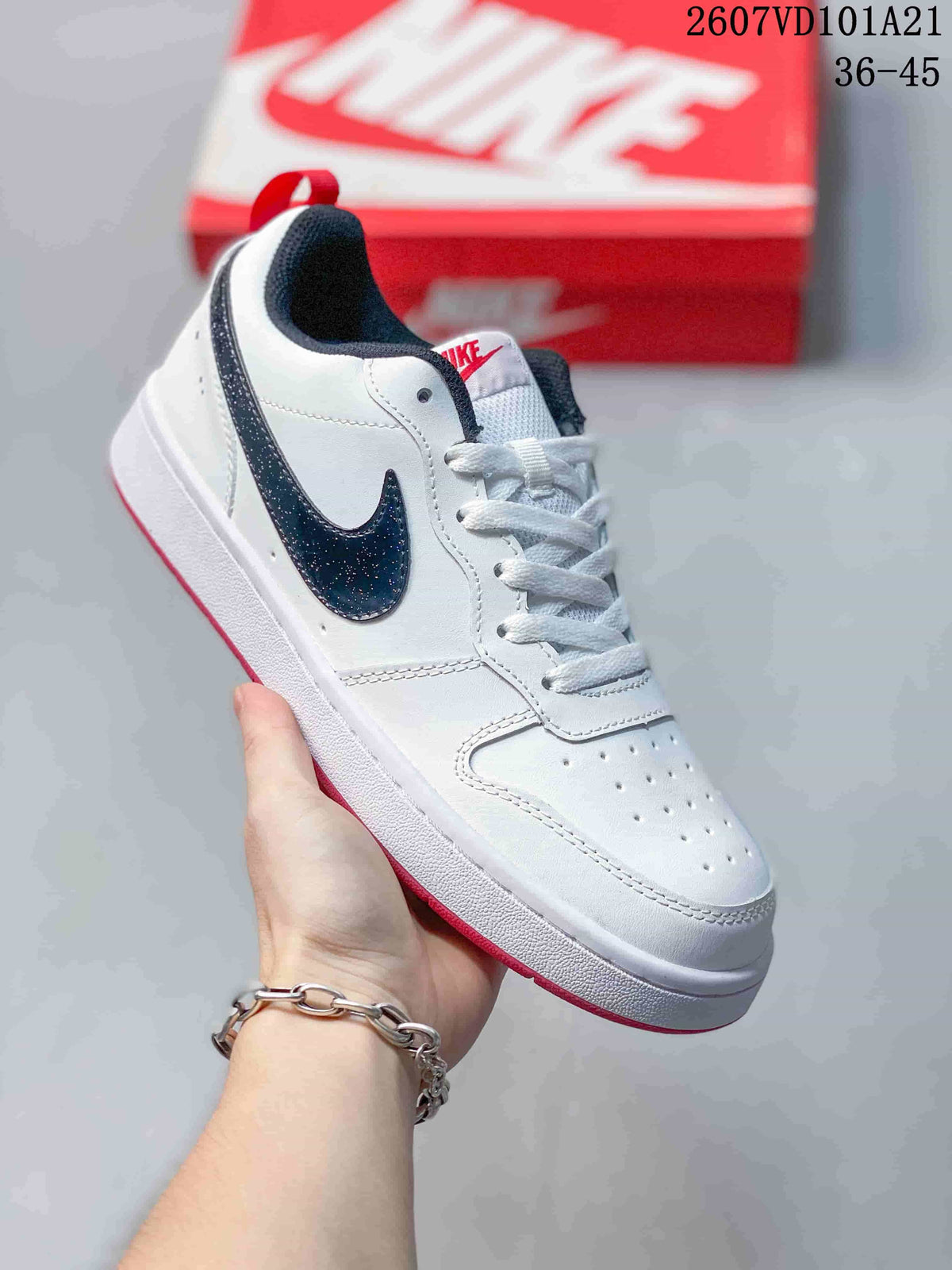 Angled side view of the white Nike sneaker with a black Swoosh, red outsole edge and red heel pull tab.