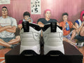 Rear view of white and black Jordan sneakers showing heel pull tabs, Jumpman heel details, and black outsole sections.