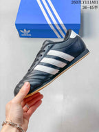 Side view of the dark gray sneaker with white stripes and a gum-colored outsole