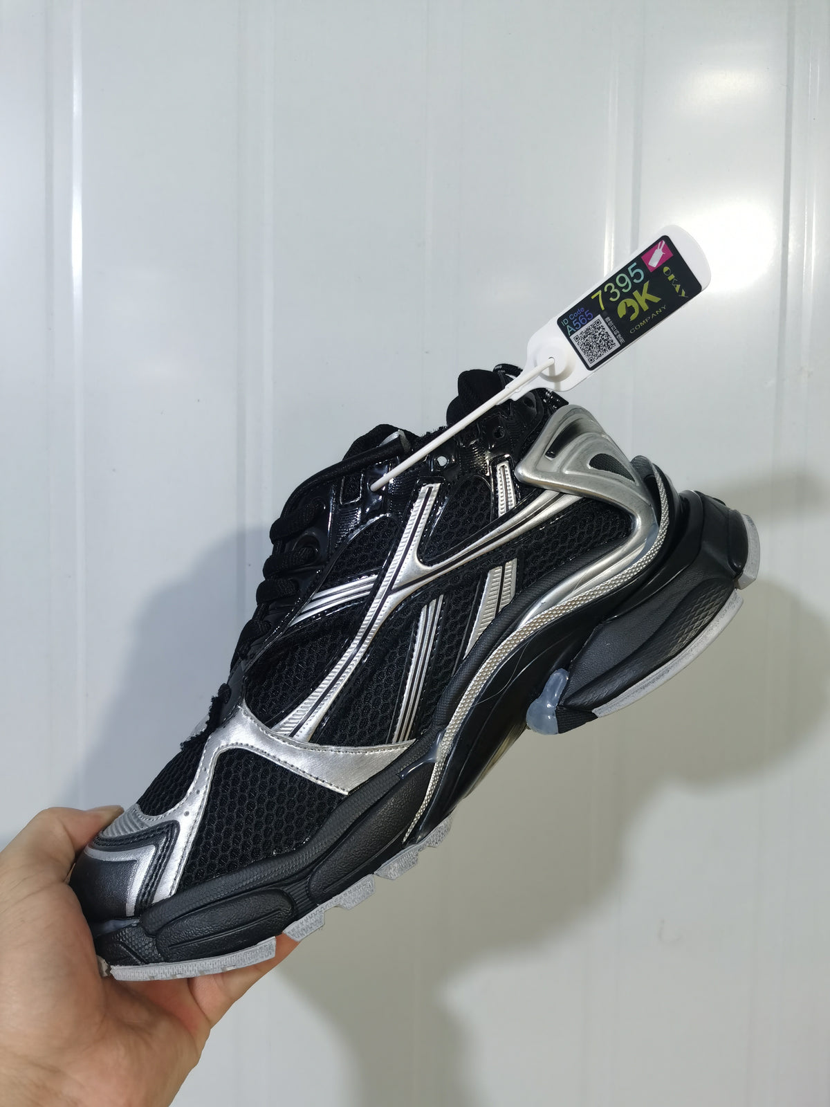 Side and top view of the black and silver Nike Runner sneaker showing layered detailing, mesh-style panels, and a hanging product tag.