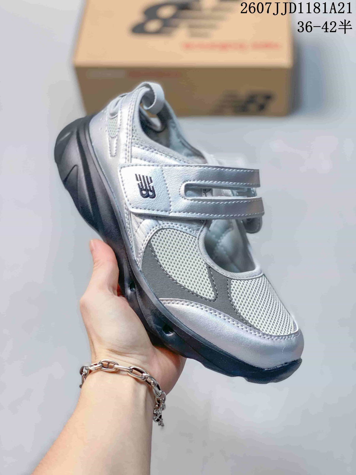 Angled side view highlighting the silver upper, New Balance logo and dark sole.