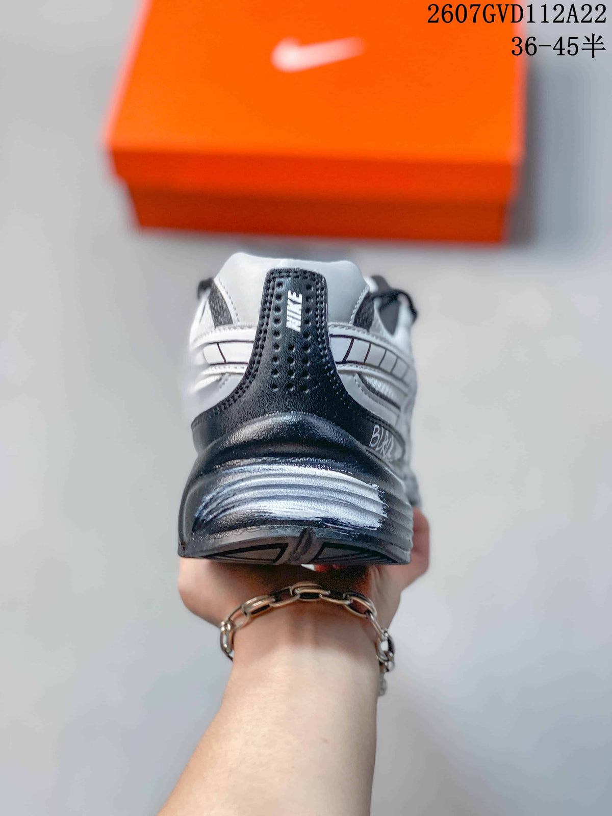 Rear view of the white and black sneaker showing the padded heel, Nike branding, and sculpted outsole.
