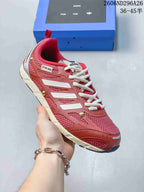 Angled side view of the red and silver sneaker showing the mesh upper, layered overlays, cream laces, and heel pull tab.