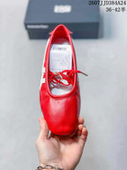 Top view of the red shoe showing its rounded toe, lace-up opening, white side detailing, and interior label.