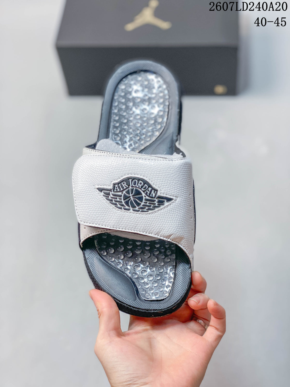 Top view of a white and navy slide showing the broad branded strap and raised textured footbed.