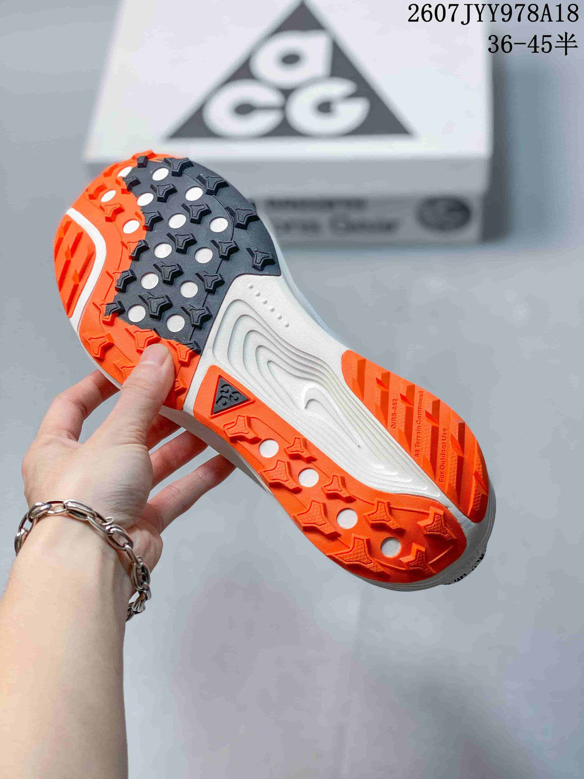 Close view of the Nike ACG Pegasus Trail outsole showing black and orange sections with a lugged tread pattern.