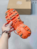 Underside view of an orange sneaker showing the sculpted outsole, traction elements, and open cushioning channels; the JYD386A26 code and 36–45 range are visible.