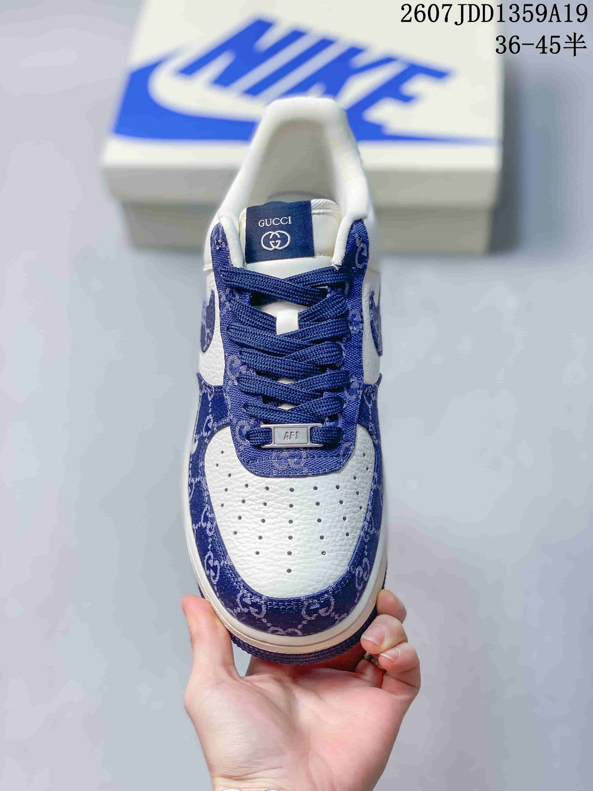 Top view of a sneaker showing the white perforated toe box, blue patterned eyestay and trim, blue laces, and tongue label.