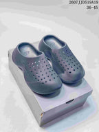 Pair of dark gray perforated slip-on clogs displayed on a box.