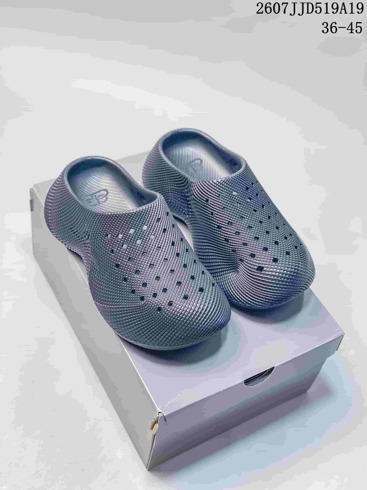 Pair of dark gray perforated slip-on clogs displayed on a box.