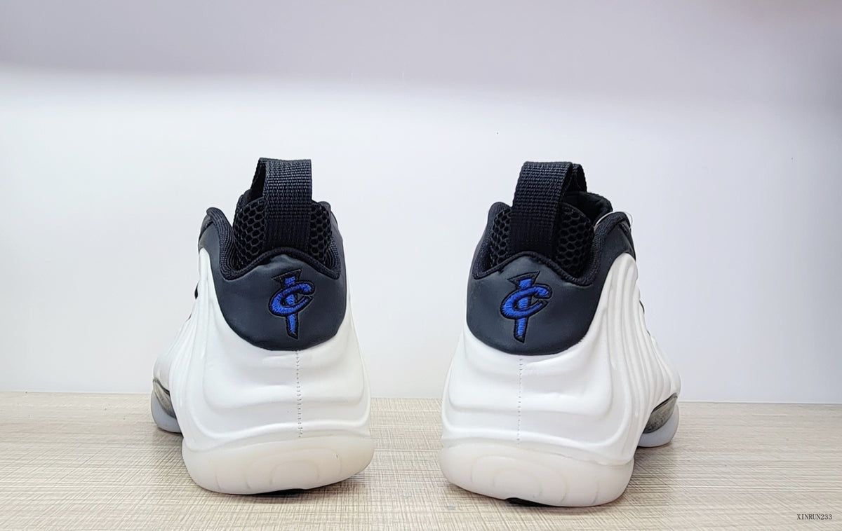 Rear view of white Nike Air Foamposite One high-tops with black collars and blue heel logos