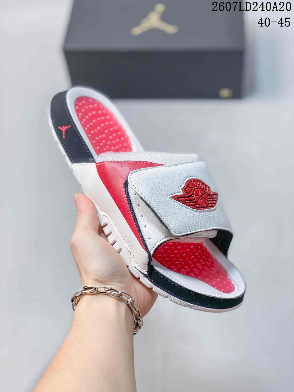 Angled view of a white, red, and black Jordan slide with an adjustable strap and textured footbed; image text shows style code 2607LD240A20 and sizes 40–45.