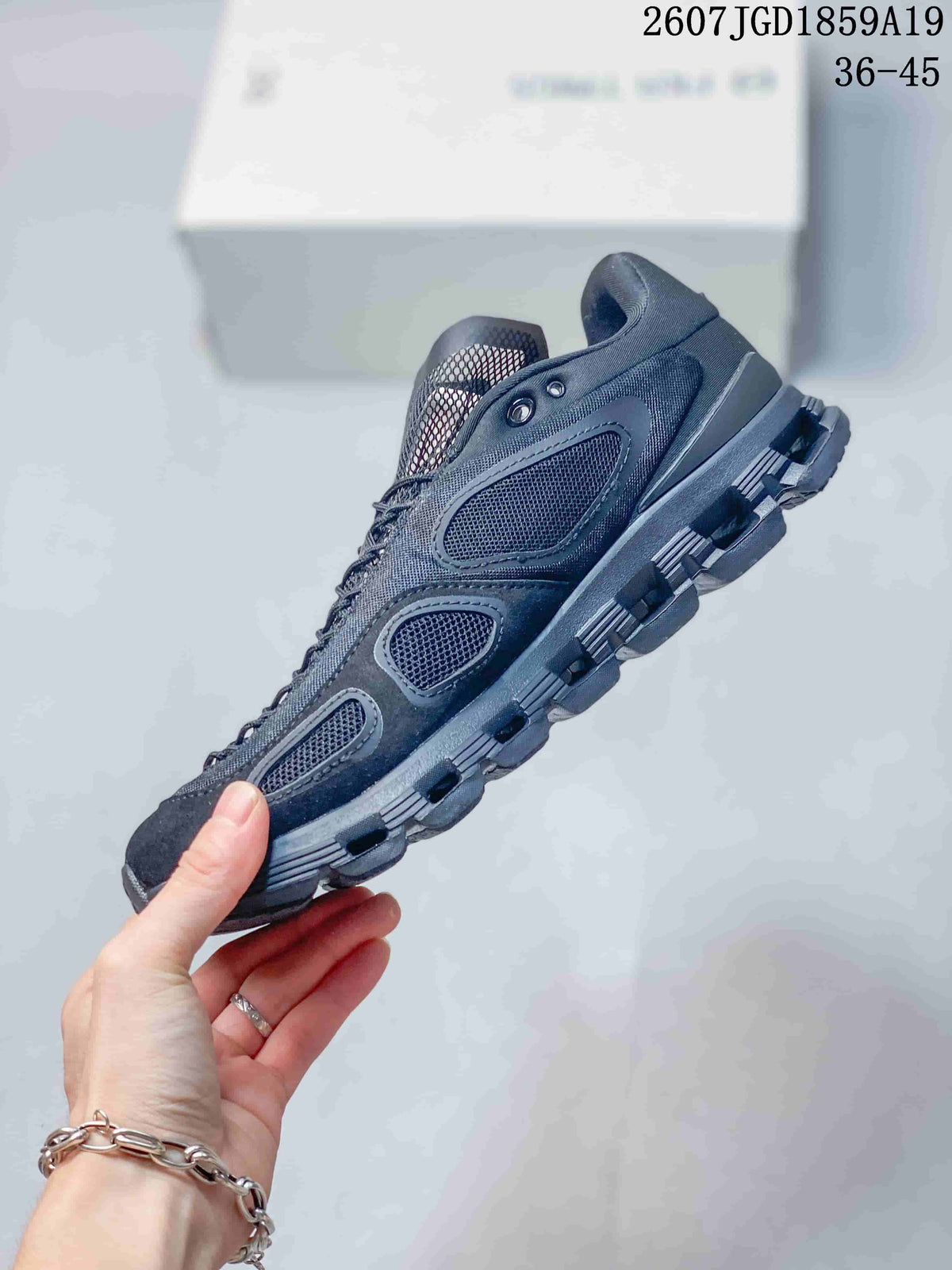 Side profile of the dark sneaker showing mesh panels, layered overlays, lace fastening, and segmented outsole.