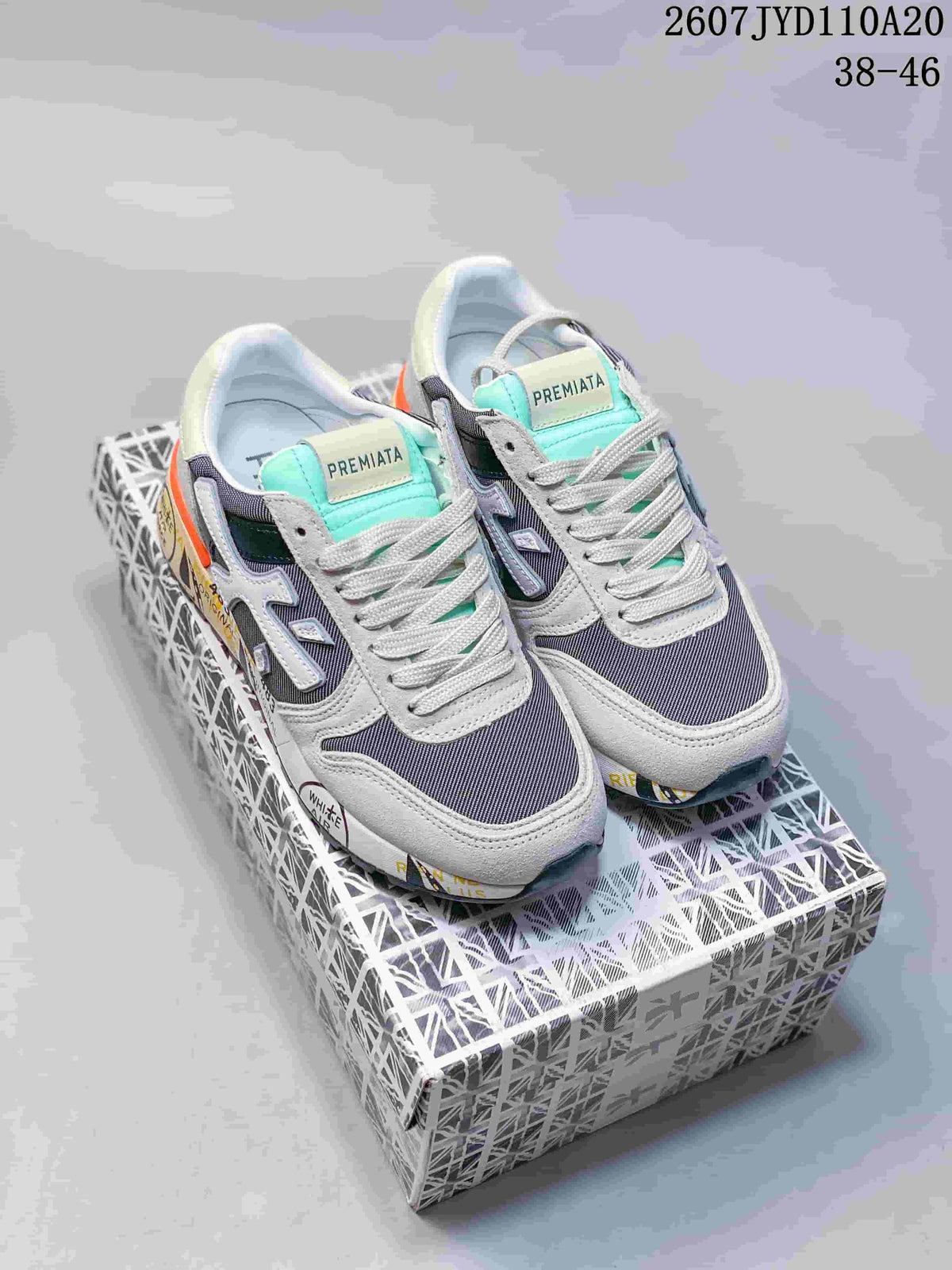 Pair of grey and navy Premiata sneakers with mint-green tongue accents, orange heel details and a patterned shoebox; image text shows 2607 TYD110A20 and 38–46.