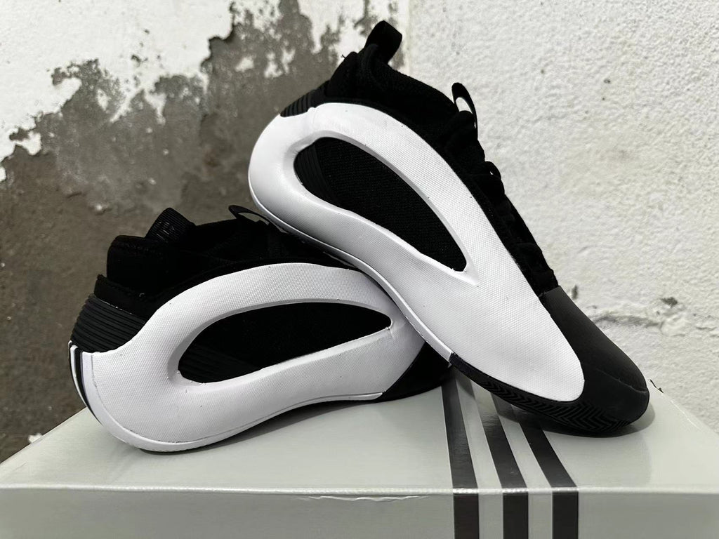 Black and white Adidas shoes displayed together, showing their side panels and outsole.