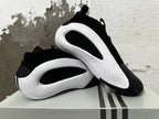 Black and white Adidas shoes displayed together, showing their side panels and outsole.