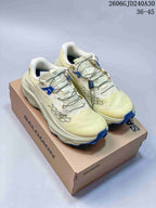 Pair of pale cream Salomon Ultra Glide 4 trail running shoes with blue outsole accents, shown on a shoebox.