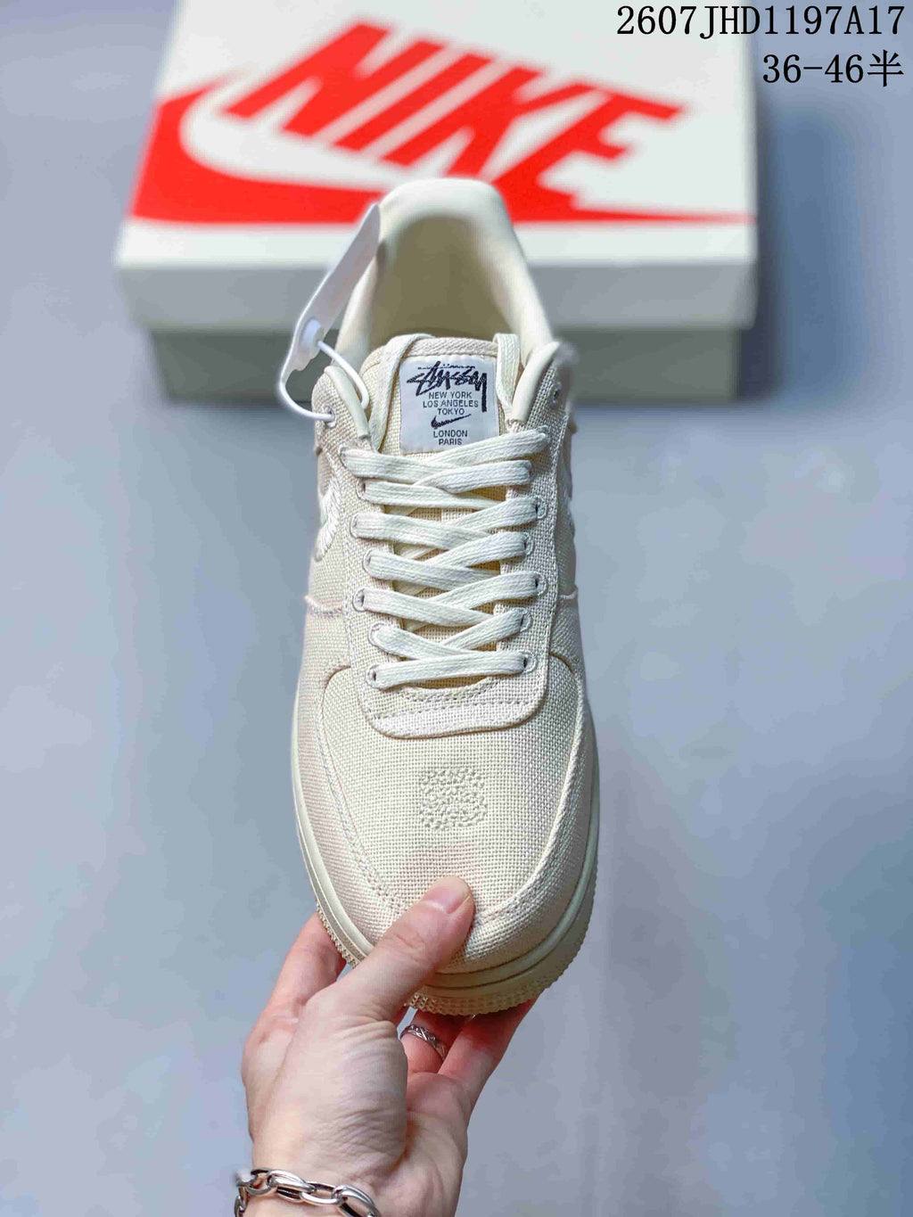 Front view of the cream sneaker showing the tonal laces, woven toe box, and Stussy-branded tongue label.
