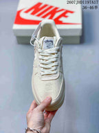 Front view of the cream sneaker showing the tonal laces, woven toe box, and Stussy-branded tongue label.