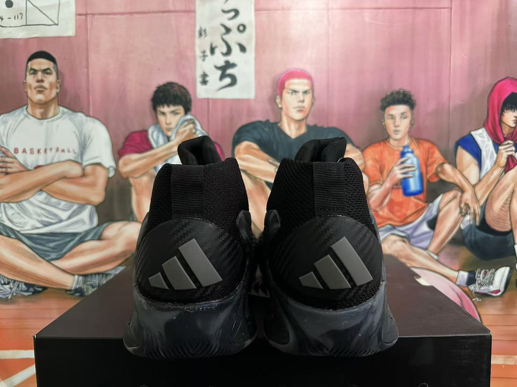 Rear view of black basketball shoes with dark gray Adidas heel stripes.