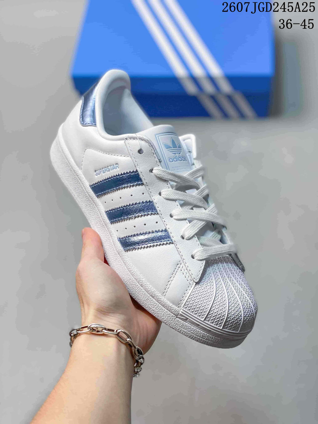 Angled side view showing the shell toe, blue stripes, Superstar side branding, and blue heel tab.