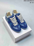 Pair of blue Maison Margiela low-top sneakers with white laces displayed on a white shoebox; style code 2607JXD185A15 and size range 36–45 are visible.