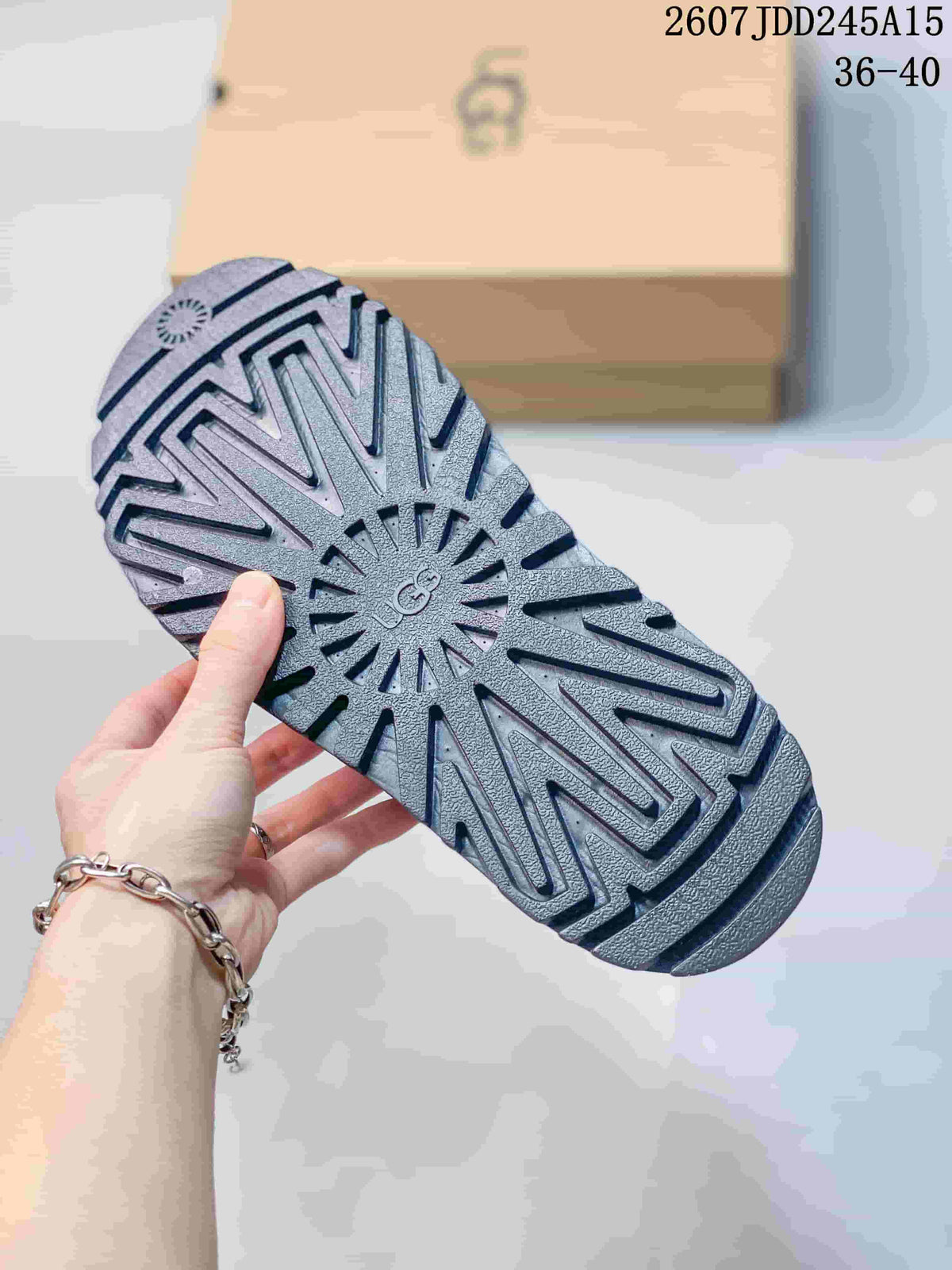 Underside of a black sandal showing the textured lug outsole and UGG marking.