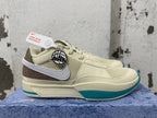 Side view of a cream Nike Ja 1 shoe with a white Swoosh, brown heel panel, and teal sole accents