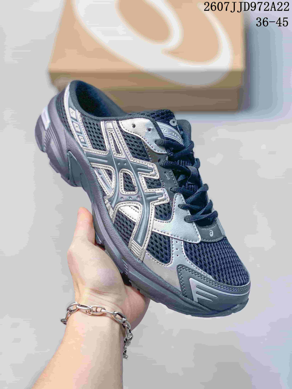 Angled side view of a navy and silver ASICS Gel-1130 sneaker held in hand.