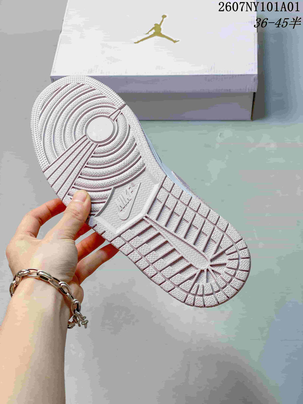 Close-up of the textured outsole on the white and pale pink low-top sneaker.