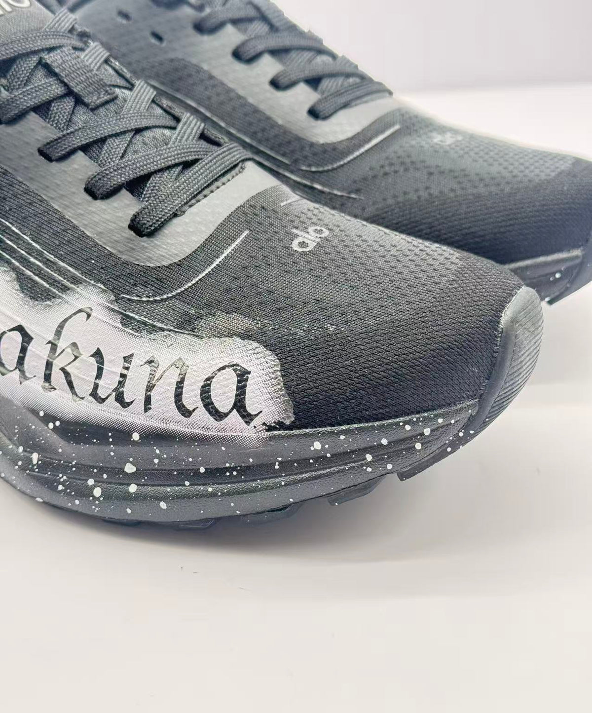 Close-up of the black textured toe box, laces, white lettering and speckled midsole.