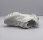 Underside angle of the white sneaker showing the tread pattern and outsole construction.