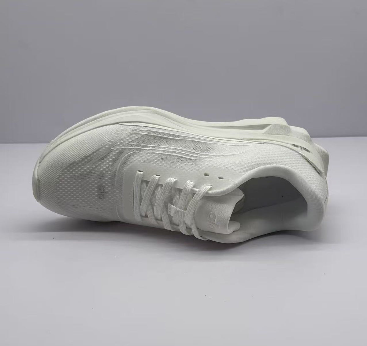 Underside angle of the white sneaker showing the tread pattern and outsole construction.