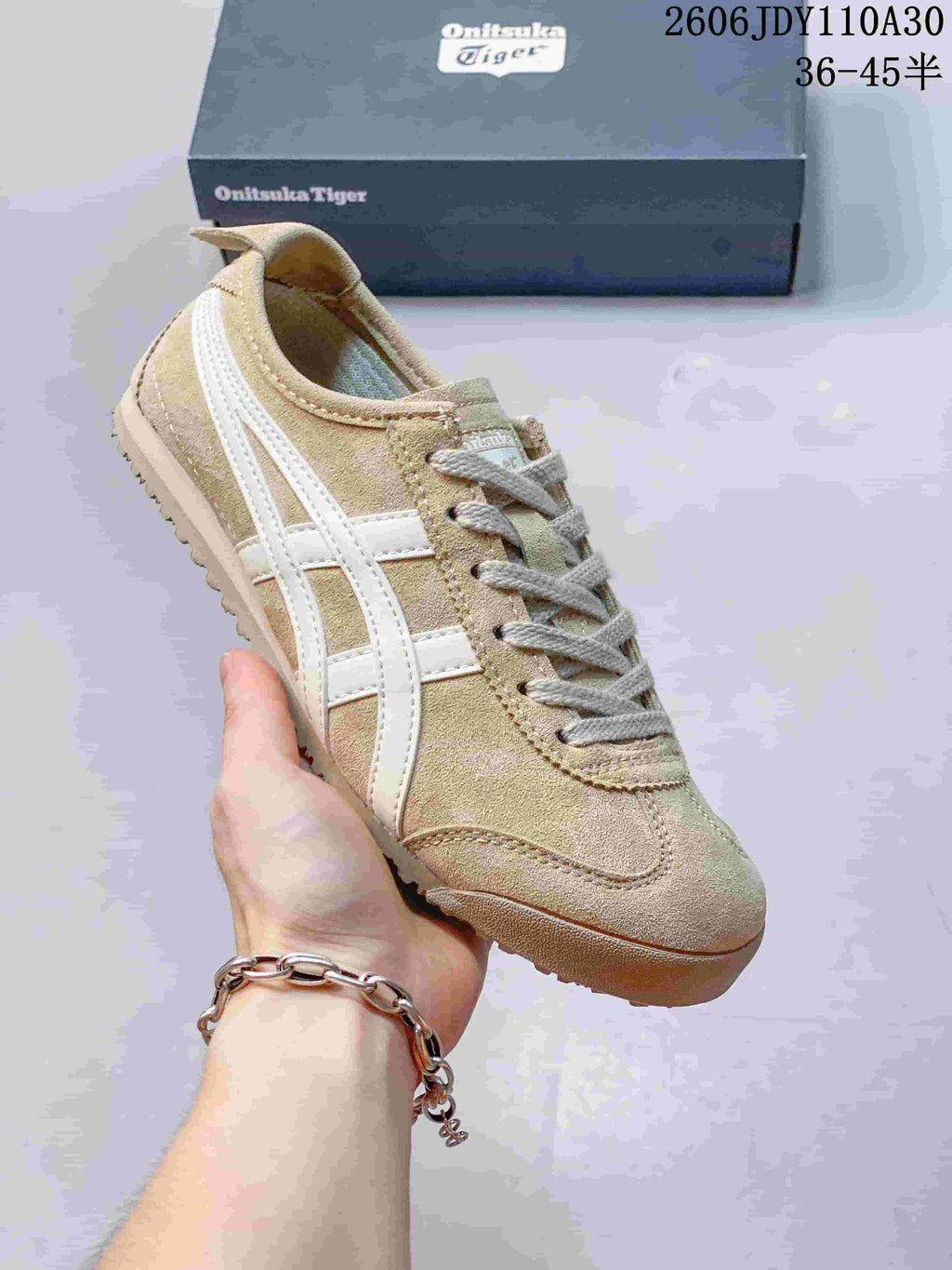 Angled view of a beige Onitsuka Tiger sneaker with white side stripes and a textured sole