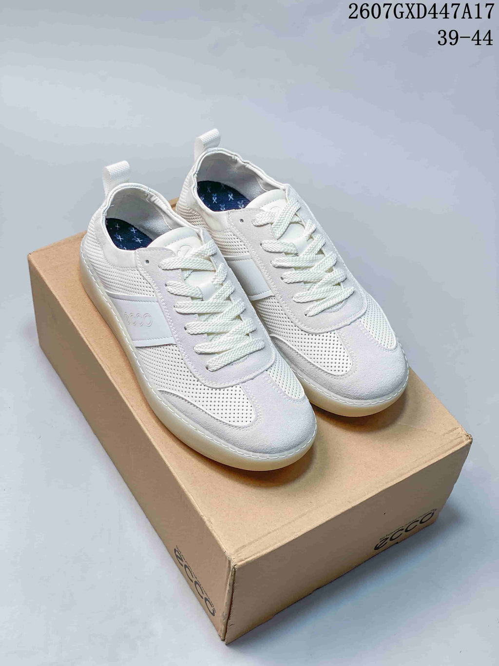 Pair of white ECCO low-top sneakers displayed on a branded shoe box, with style code 2607GXD447A17 and size range 39–44 visible above.