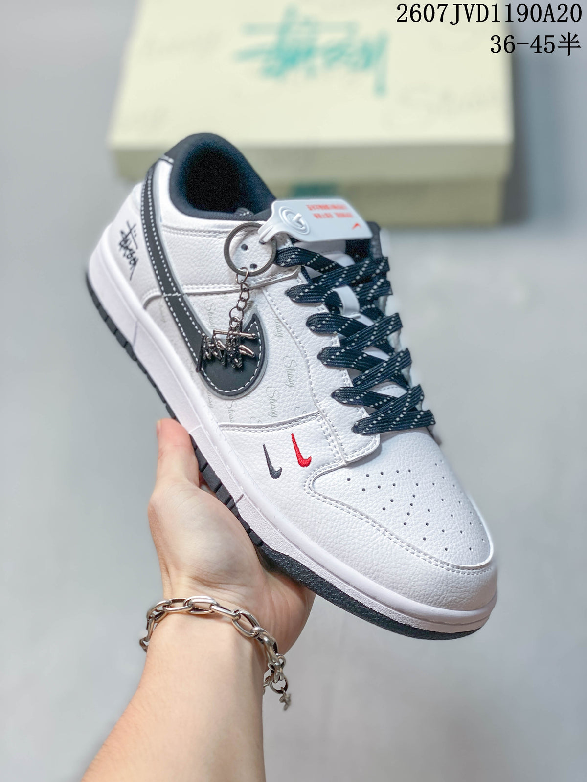 Angled side view of the white and black sneaker showing the Swoosh, decorative attachment, side graphics, and dark outsole.