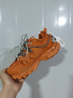 Close angled view of the orange Balenciaga Track 7000 sneaker showing the layered upper, mesh sections, rugged sole, and contrasting laces.