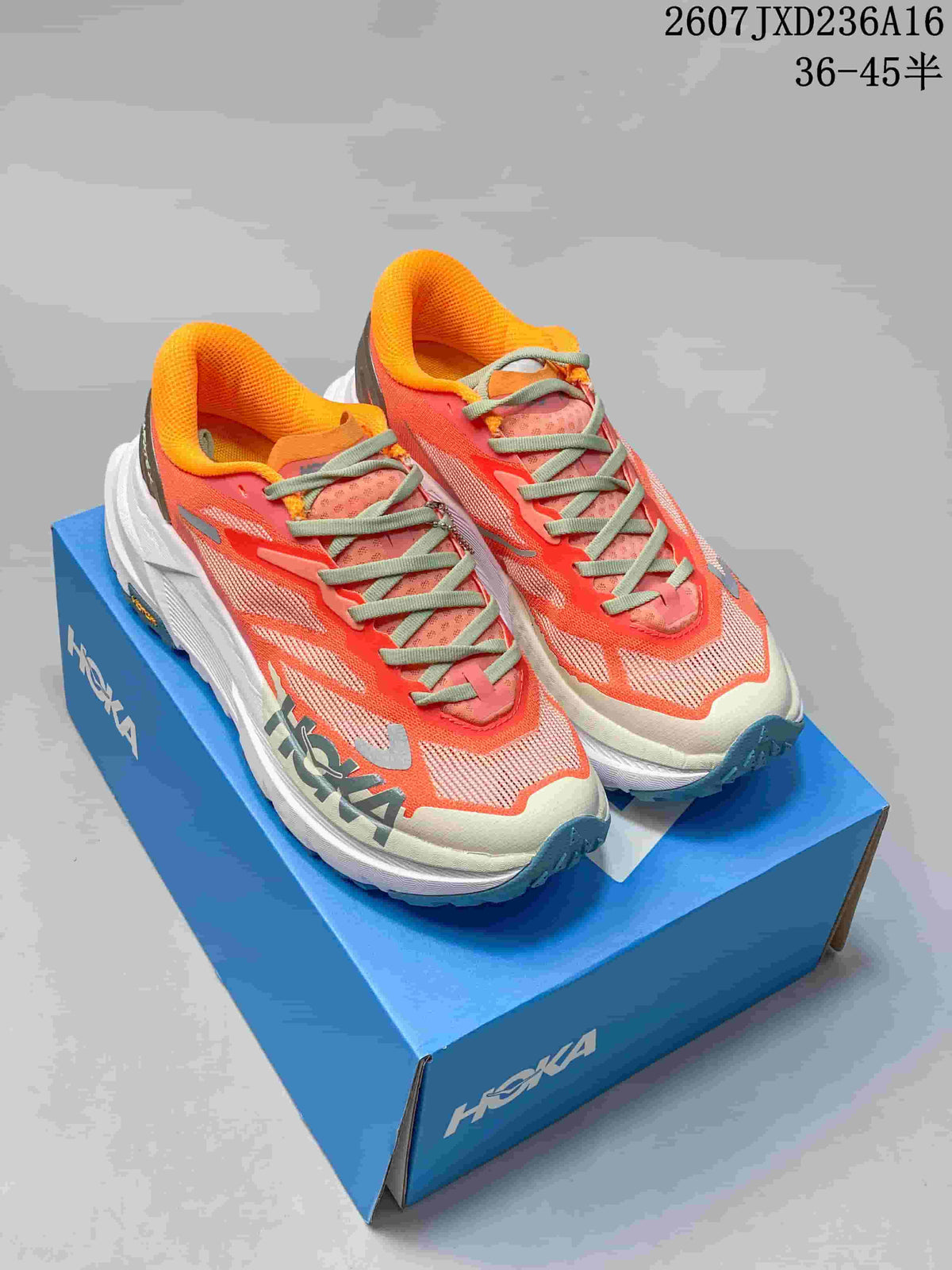 Pair of coral Hoka MAFATE X trail running shoes displayed on a blue Hoka shoebox, showing the padded collars, white midsoles, and teal outsole accents.