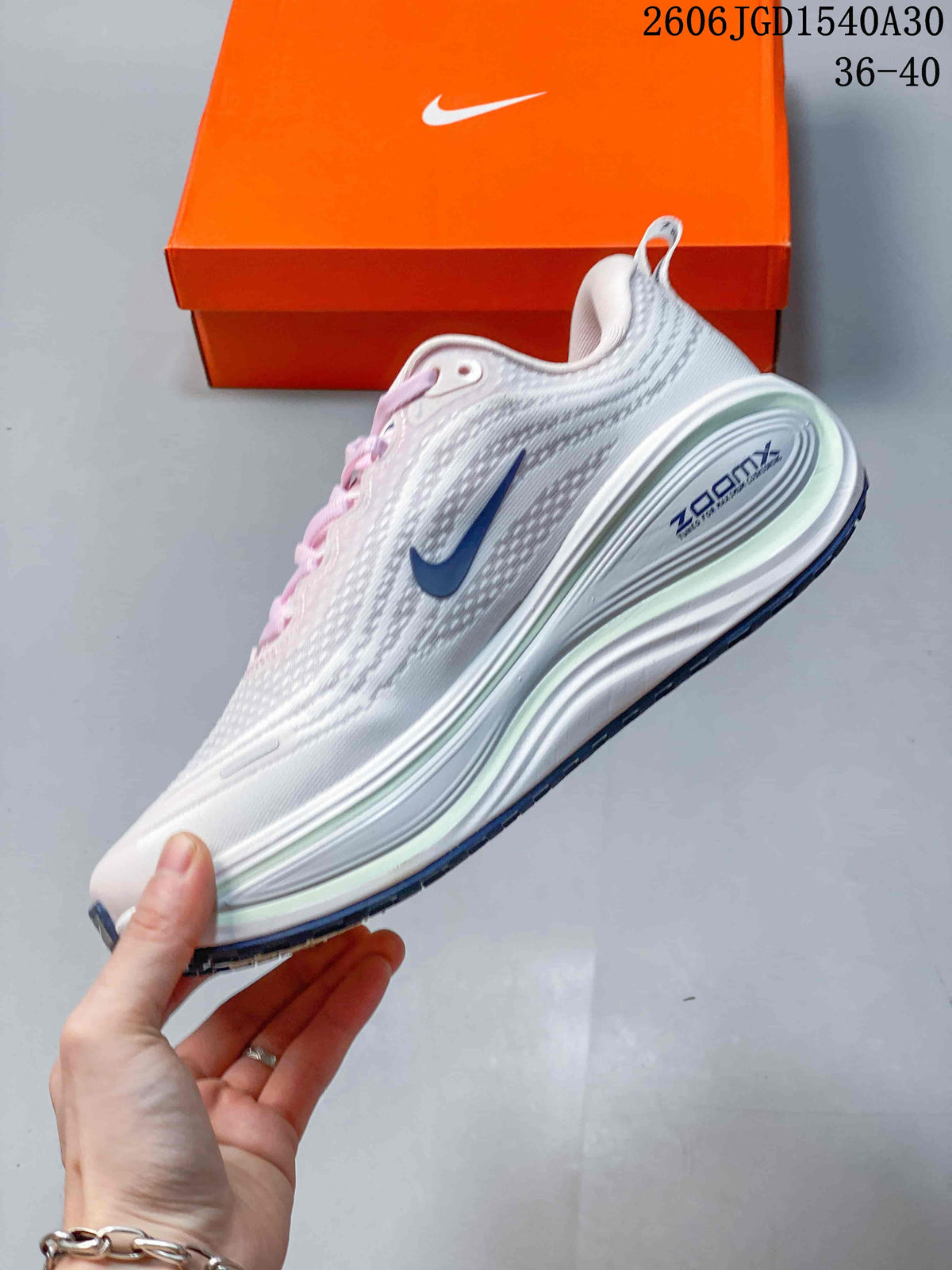 Side view of a white Nike Vomero Plus running shoe with a blue Swoosh and sculpted midsole.