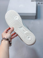 Bottom view of the white sneaker showing a circular-patterned rubber outsole.